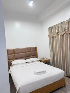 a bedroom with a large bed with white sheets and a window at Jeamco Royal Hotel-Palawan in Puerto Princesa City