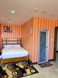 プエルト・プリンセサにあるJeamco Royal Hotel-Palawanのオレンジ色のストライプの壁、ベッド付きのベッドルーム1室が備わります。