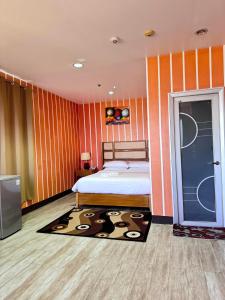 - une chambre avec un lit aux murs rayés d'orange dans l'établissement Jeamco Royal Hotel-Palawan, à Puerto Princesa