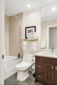 a white bathroom with a toilet and a sink at Scenic 3BR Penthouse Suite w/ Rooftop Lake View in Harrison Hot Springs