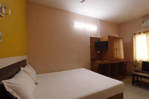 a bedroom with a white bed and a television at The Royal Comfort in Bangalore