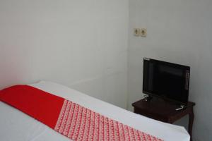 OYO 93784 Kost Bu Eli Syariah في Ngadipuro: غرفة نوم بسرير وتلفزيون على طاولة