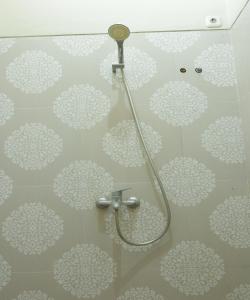 y baño con ducha y flores blancas en la pared. en OYO 93784 Kost Bu Eli Syariah en Ngadipuro