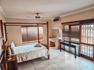 a bedroom with a bed and a desk and windows at Lethabong Lodge in Thabazimbi