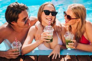 a group of three people sitting in a pool drinking milkshakes at Desert Residency camp Jaisalmer with swimming pool in Jaisalmer