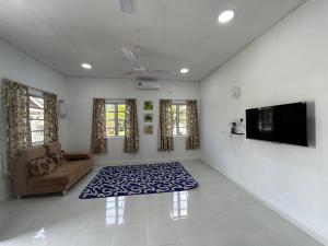 a living room with a couch and a flat screen tv at Cantik-La Homestay 3 Bilik Kuala Terengganu in Bukit Payong