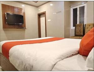a bedroom with a bed and a flat screen tv at Hotel Grand Inn, Warangal in Warangal