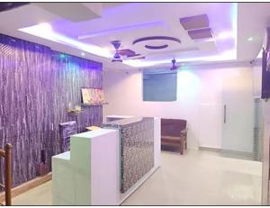 a room with a tv and a ceiling with purple lights at Hotel Grand Inn, Warangal in Warangal