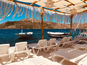 un grupo de sillas y barcos en el agua en Seyyah Suites Bozburun, en Marmaris