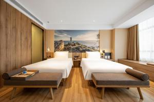 a hotel room with two beds and a painting on the wall at Atour Hotel High Speed Railway Station Maoming in Maoming