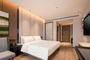 a bedroom with a white bed and a television at Atour Hotel Nanjing Medical Valley Xinghuo Road in Nanjing