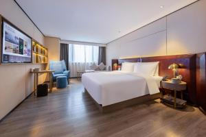 a bedroom with a large white bed and a desk at Atour X Hotel Haikou International Trade Center in Haikou