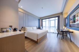 JiangningにあるAtour X Hotel Nanjing Jiangning Future Internet Townのベッド、デスク、キッチンが備わるホテルルームです。