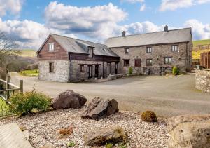 une ancienne maison en pierre avec des rochers devant elle dans l'établissement Beacons View Farm Cottages, à Merthyr Cynog