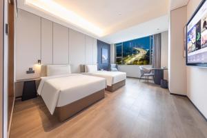 a hotel room with two beds and a flat screen tv at Atour X Hotel Guangzhou Avenue South Pazhou Convention and Exhibition Center in Guangzhou