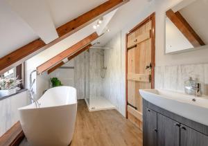 La salle de bains est pourvue d'une baignoire blanche et d'une douche. dans l'établissement Beacons View Farm Cottages, à Merthyr Cynog