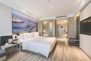een slaapkamer met een groot wit bed en een televisie bij Atour Hotel Ningbo Airport Yinzhou Avenue in Ningbo