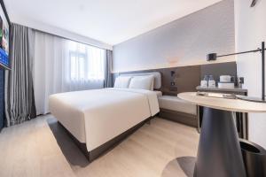 a hotel room with a white bed and a table at Atour Light Hotel Shenzhen North Station Hongshan Metro Station in Lung Wa