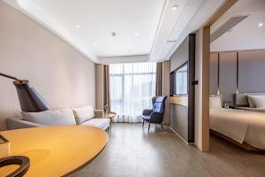 una camera d'albergo con letto, divano e tavolo di Atour Hotel Ningbo Yinzhou Wanda Mingzhouli a Ningbo