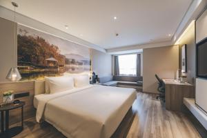 南京市にあるAtour Hotel Nanjing South Stationの大きなベッドとデスクが備わるホテルルームです。