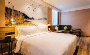 a bedroom with a large white bed and a couch at Atour Hotel South Business Zone Ningbo in Ningbo