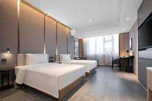 um quarto de hotel com duas camas e uma televisão em Atour Hotel Ningbo Zhenhai New City em Ningbo