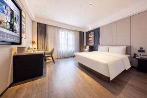 a hotel room with a white bed and a desk at Atour Hotel Guangzhou Baiyun Jiahe Hebian in Guangzhou