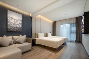 三亜市にあるAtour Hotel Sanya Bay Fenghuang Roadのベッドとソファ付きのホテルルーム