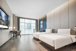 Atour Hotel Chengdu Jinhua Wanda Liulichang في تشنغدو: غرفة فندقية بسريرين وتلفزيون بشاشة مسطحة