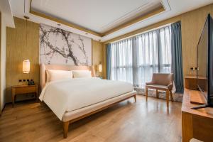 - une chambre avec un grand lit blanc et une télévision dans l'établissement Atour S Hotel Guangzhou Beijing Road Tianzi Wharf, à Canton