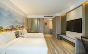 una camera d'albergo con due letti e una TV a schermo piatto di Atour Hotel Foshan Nanhai Qiandeng Lake Guicheng a Nanhai