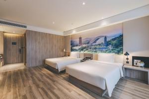 duas camas num quarto de hotel com um quadro na parede em Atour Hotel Nanjing South Station em Nanquim