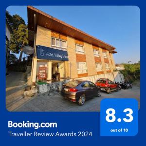 a building with two cars parked in front of it at Hotel Valley Vista in Mussoorie