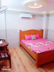 a bedroom with a wooden bed with pink sheets at Nhà Nghỉ Xuân Lan in Ấp An Mỹ