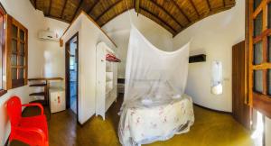 a bedroom with a bed with a mosquito net at Pousada Aldeia in Ilha de Boipeba