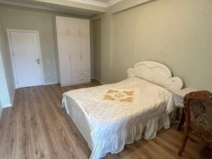 Schlafzimmer mit einem weißen Bett und Holzboden in der Unterkunft Mirvari in Sumqayıt