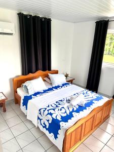 1 dormitorio con 1 cama grande con sábanas azules y blancas en ATITAUTU Guest House, en Tautira