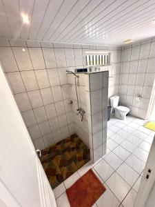 Baño de azulejos blancos con aseo y escalera en ATITAUTU Guest House, en Tautira
