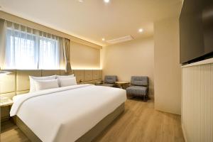 una habitación de hotel con una gran cama blanca y una ventana en Denbasta Hotel Daeyeon en Busan