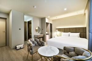 1 dormitorio con 1 cama, 2 sillas y mesa en Denbasta Hotel Daeyeon en Busan