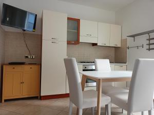 una cucina con tavolo bianco e sedie bianche di Da Eolo - Appartamento al mare a Grottammare