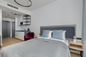 a bedroom with a large bed and a red chair at Modern Studios in the Centre of Poznań by Renters in Poznań