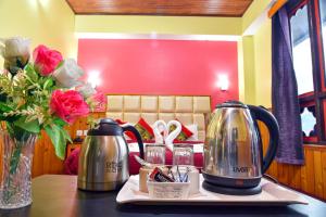 a table with a tea kettle and flowers on it at Rufina Lachung Heritage in Lachung