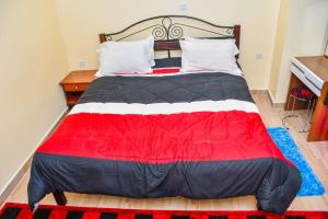 a large bed with a red and black comforter at Gatville Serene Gardens in Kiserian