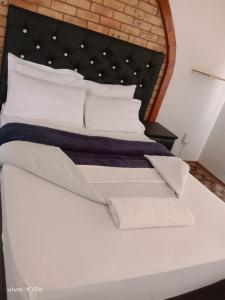 1 dormitorio con cama blanca y almohadas blancas en Rz guest house, en Mahikeng