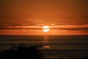 a sunset over the ocean with the sun in the sky at Big Heart Beach in Ruatapu
