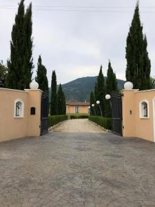 une allée menant à un bâtiment avec un portail et des arbres dans l'établissement Villa Arianna, à Cori