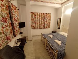 a bedroom with a bed and a chair and a window at Little Peepal House in Udaipur
