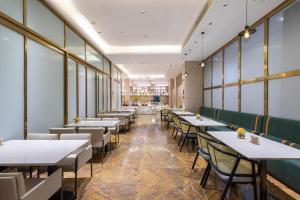 Atour X Hotel Haikou International Trade Center في هايكو: غرفة طعام مع طاولات وكراسي ونوافذ