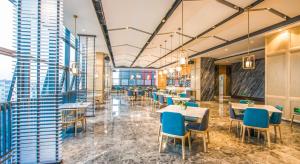 a dining room with tables and chairs and windows at Atour Hotel Foshan Nanhai Qiandeng Lake Guicheng in Nanhai